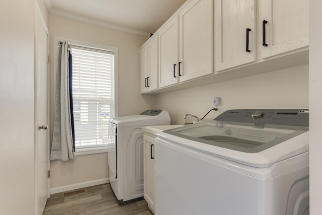 washroom featuring separate washer and dryer, cabinets, crown molding, and wood-type flooring