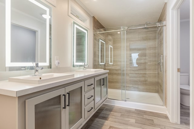 bathroom with hardwood / wood-style floors, vanity, toilet, ornamental molding, and walk in shower