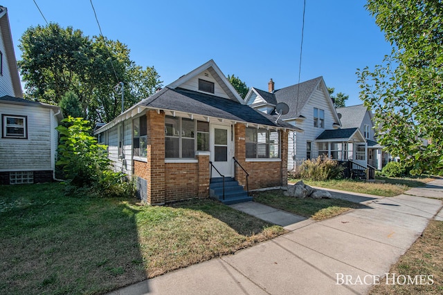 bungalow with a front yard and a sunroom