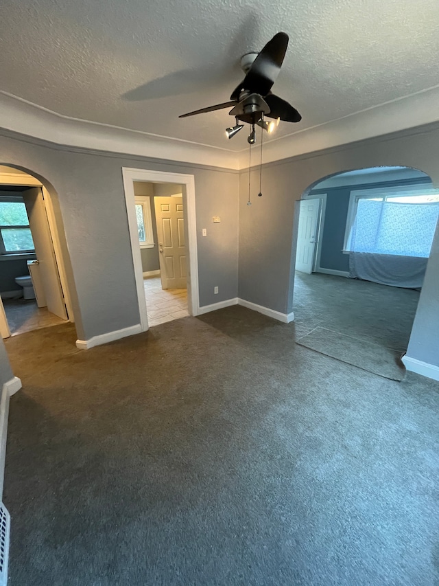 unfurnished living room with carpet flooring, ceiling fan, and a textured ceiling