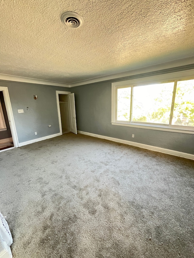 unfurnished bedroom featuring carpet, a textured ceiling, and crown molding