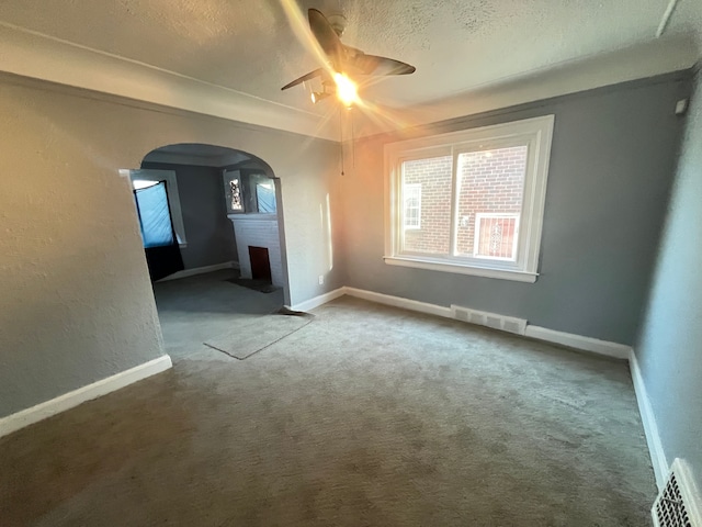 empty room featuring visible vents, arched walkways, ceiling fan, and a textured ceiling