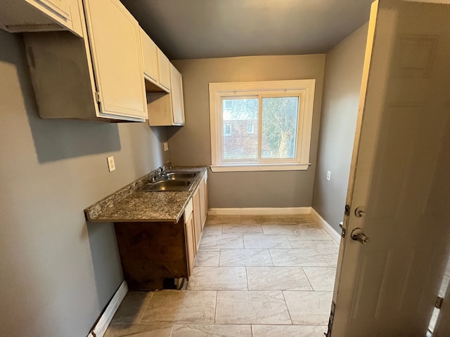 kitchen featuring baseboards and a sink
