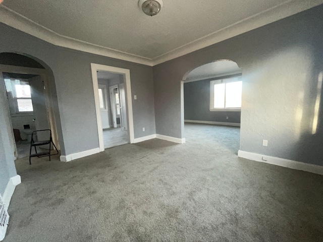 spare room with arched walkways, carpet, and baseboards
