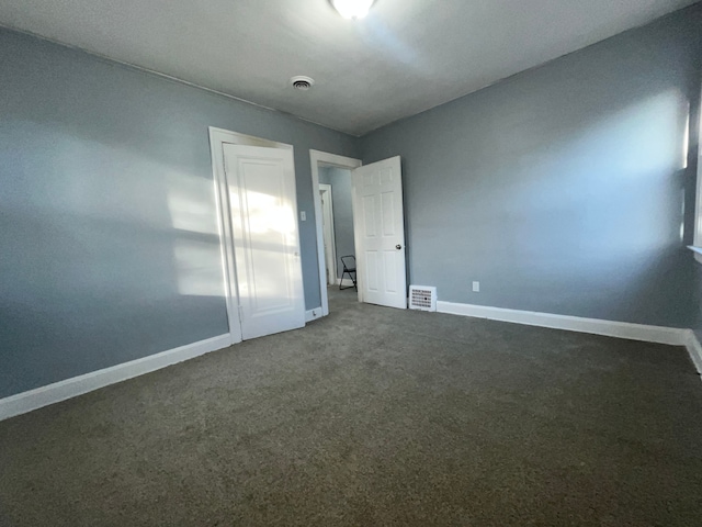 unfurnished bedroom with baseboards, visible vents, a closet, and dark colored carpet