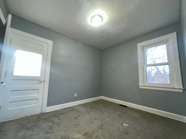 carpeted empty room featuring baseboards and visible vents