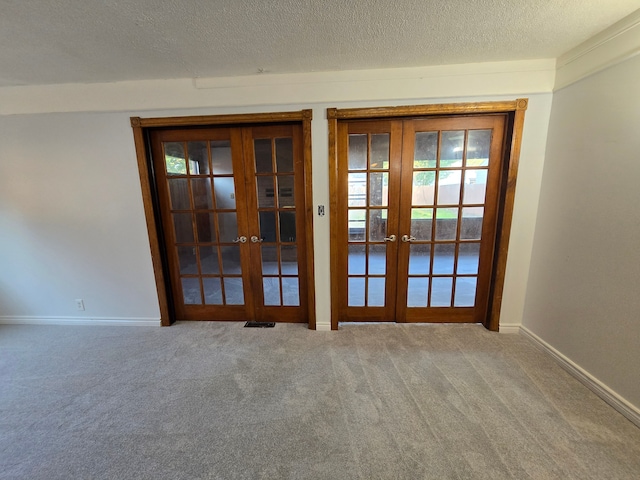 carpeted empty room with french doors and a textured ceiling