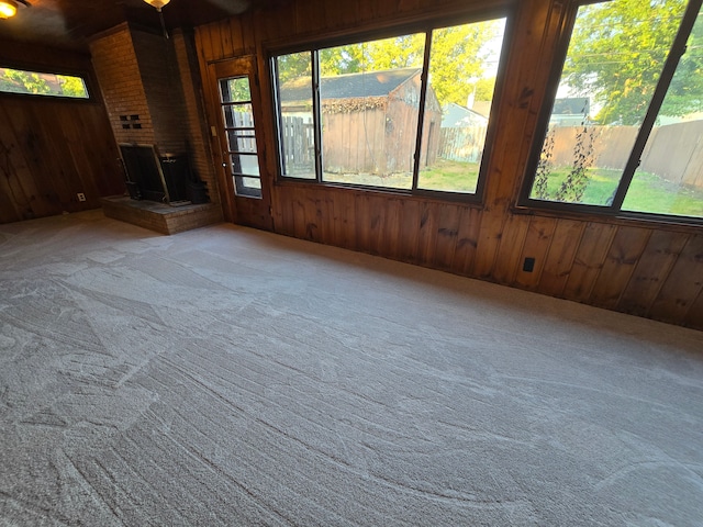 empty room featuring carpet, a fireplace, and wood walls