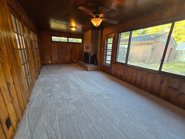 interior space featuring ceiling fan, a wood stove, and wooden walls