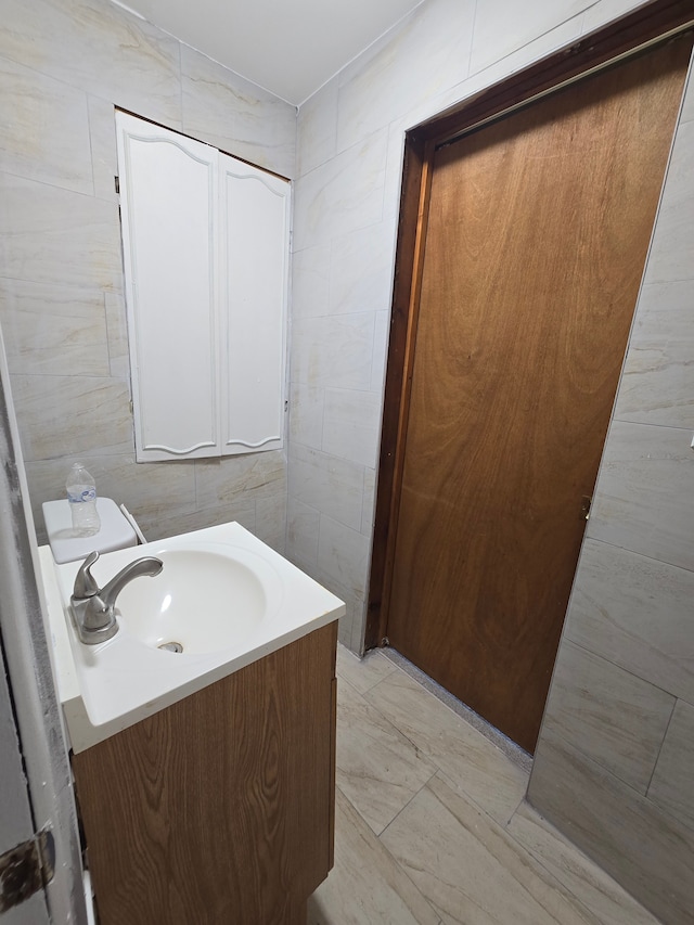 bathroom featuring vanity, toilet, and tile walls