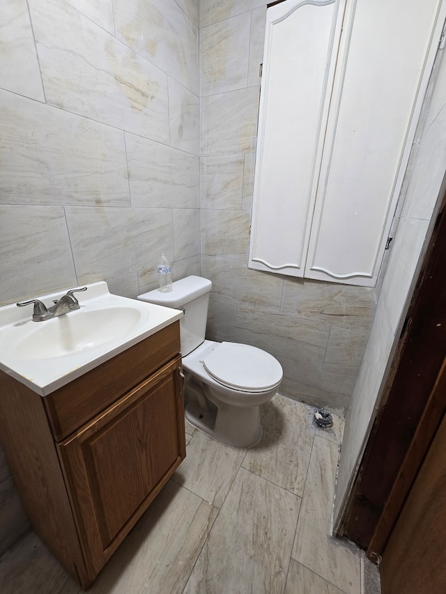 bathroom featuring vanity, toilet, and tile walls