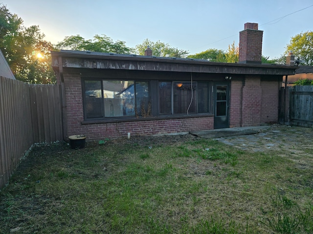 back house at dusk featuring a yard