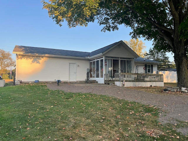 view of front facade with a front lawn, a wooden deck, and a sunroom