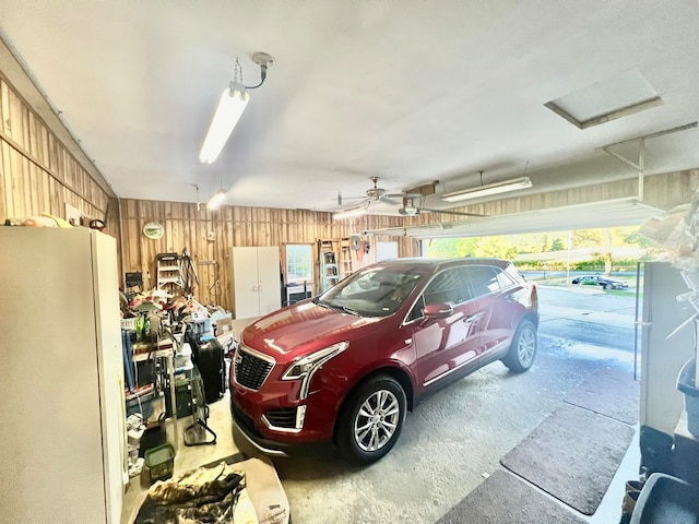 garage featuring white fridge, a garage door opener, and wood walls