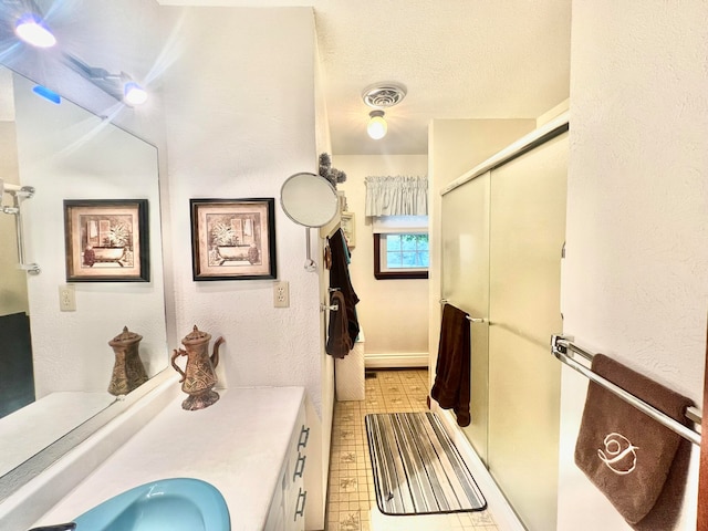 bathroom with a shower with door, vanity, and a textured ceiling