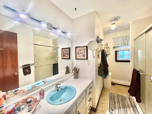 bathroom with vanity, an enclosed shower, and a textured ceiling