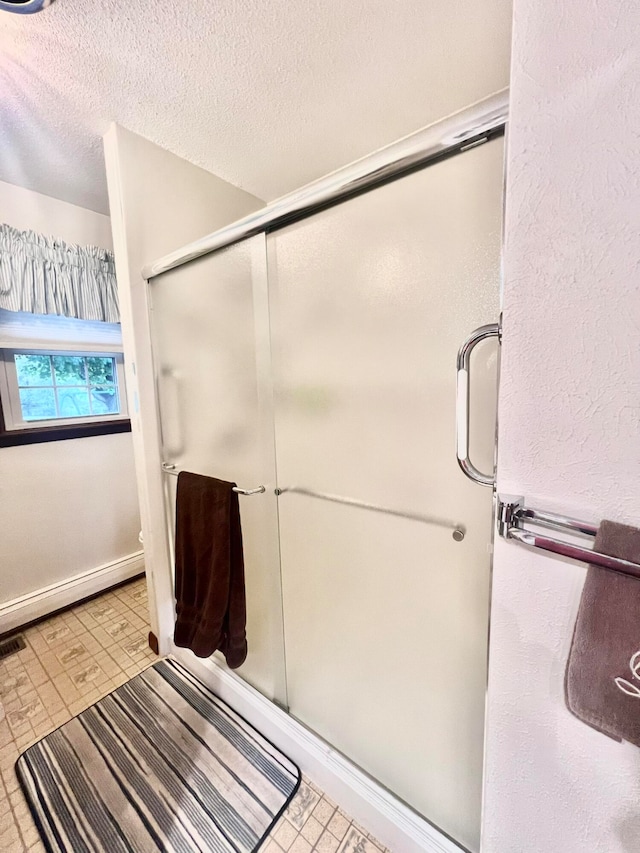 bathroom with a shower with door, a textured ceiling, and a baseboard radiator