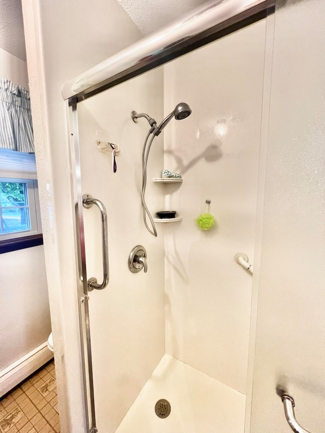 bathroom featuring a textured ceiling, toilet, a shower, and baseboard heating