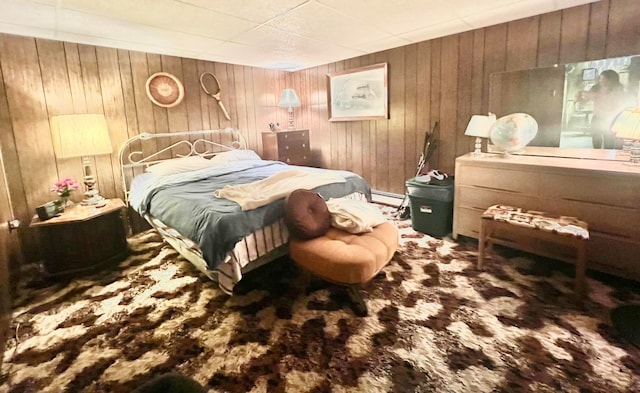 bedroom featuring a baseboard heating unit, carpet floors, and wooden walls