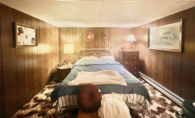 bedroom with wooden walls and a baseboard radiator