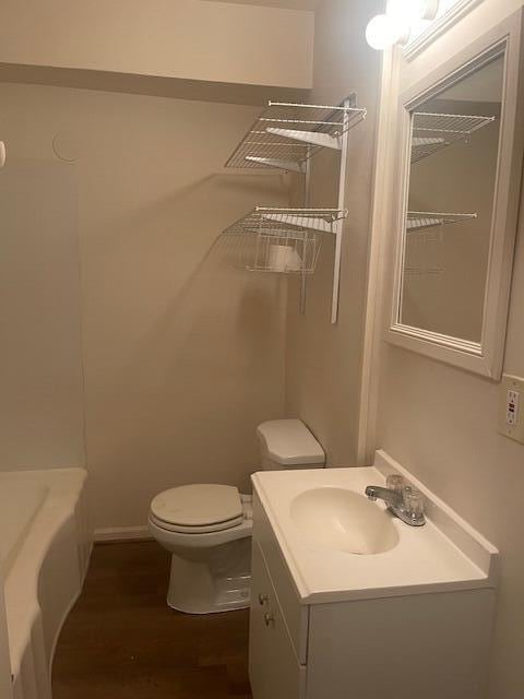 bathroom with a bathtub, vanity, wood-type flooring, and toilet