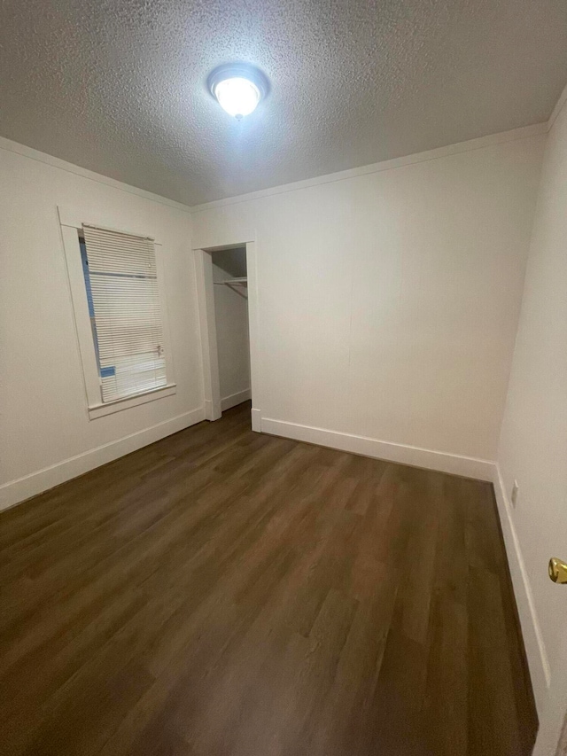 unfurnished bedroom with dark hardwood / wood-style floors, crown molding, a textured ceiling, and a closet