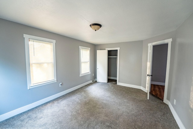 unfurnished bedroom with a closet and dark colored carpet