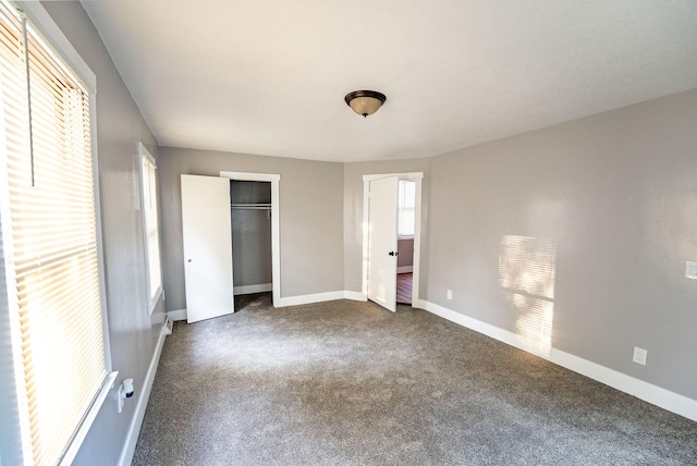 unfurnished bedroom featuring a closet and dark carpet