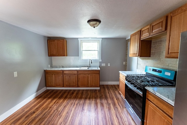 kitchen featuring backsplash, sink, dark hardwood / wood-style floors, a textured ceiling, and appliances with stainless steel finishes