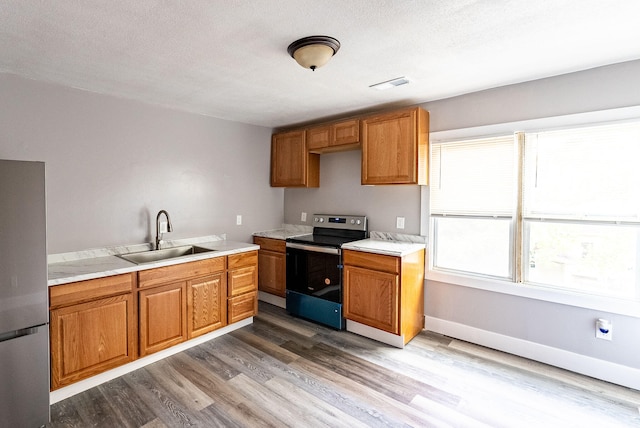 kitchen with hardwood / wood-style floors, a textured ceiling, stainless steel appliances, and sink