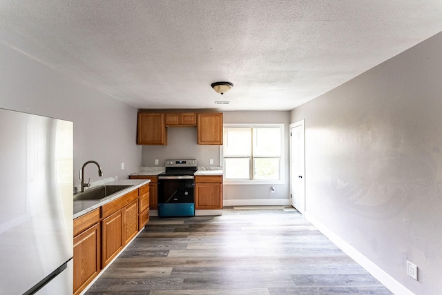 kitchen featuring hardwood / wood-style floors, sink, stainless steel appliances, and a textured ceiling