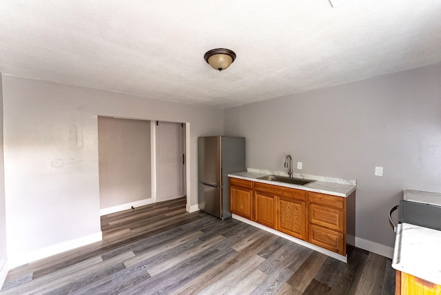 kitchen featuring a textured ceiling, dark hardwood / wood-style flooring, stainless steel refrigerator, and sink