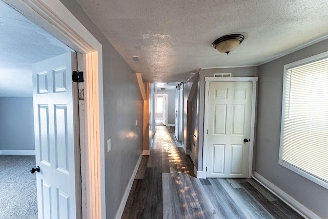 hallway with a textured ceiling and dark hardwood / wood-style floors