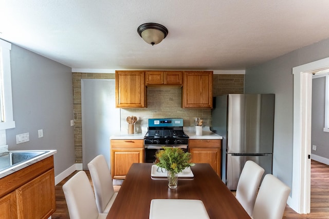 kitchen featuring backsplash, sink, a textured ceiling, light hardwood / wood-style floors, and stainless steel appliances