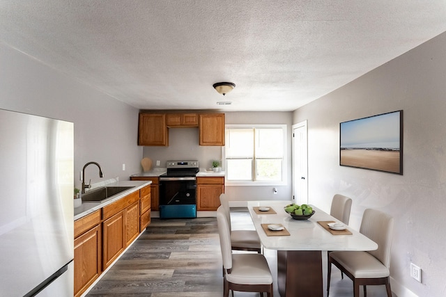 kitchen featuring sink, a kitchen breakfast bar, dark hardwood / wood-style floors, a textured ceiling, and appliances with stainless steel finishes