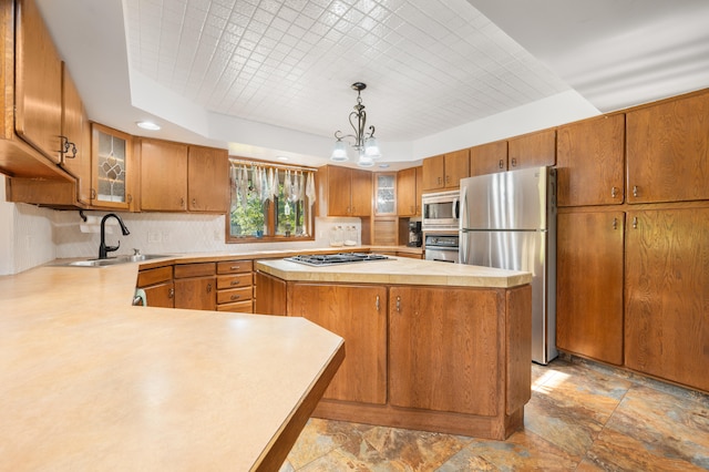 kitchen with pendant lighting, a center island, sink, appliances with stainless steel finishes, and a notable chandelier