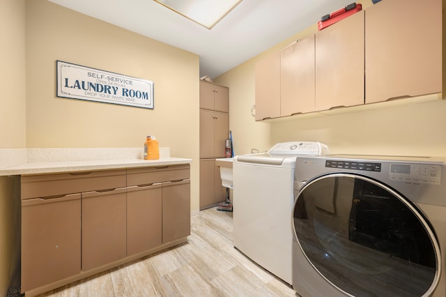 laundry room featuring washer and clothes dryer, cabinets, and light wood-type flooring