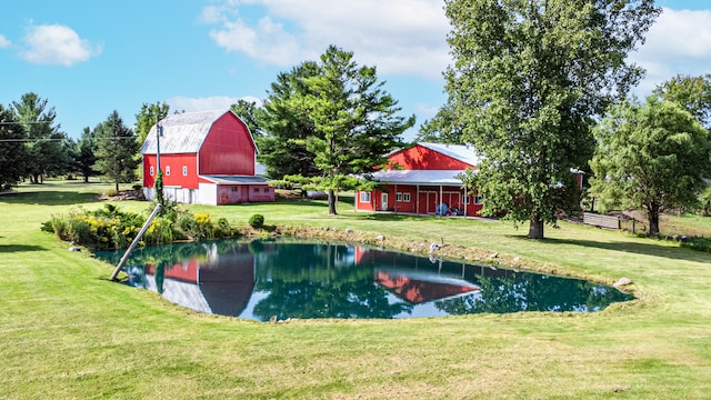 view of pool with an outbuilding, a yard, and a water view