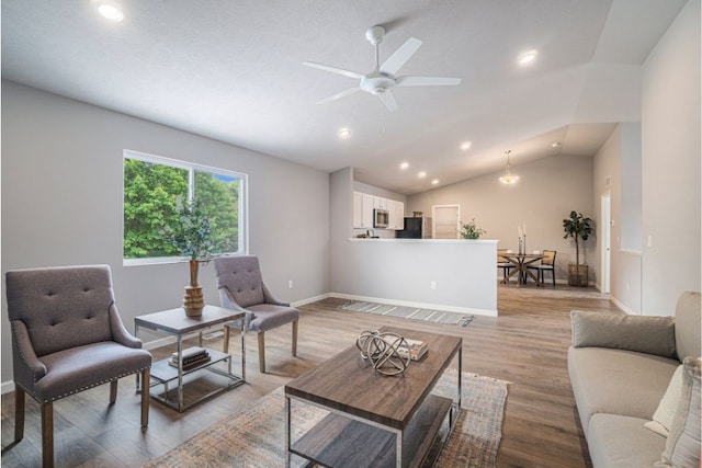 living room with ceiling fan, light hardwood / wood-style floors, and vaulted ceiling