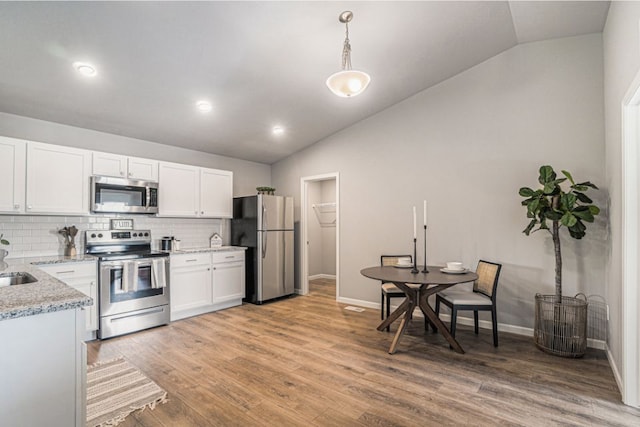 kitchen featuring white cabinets, wood-type flooring, lofted ceiling, and stainless steel appliances