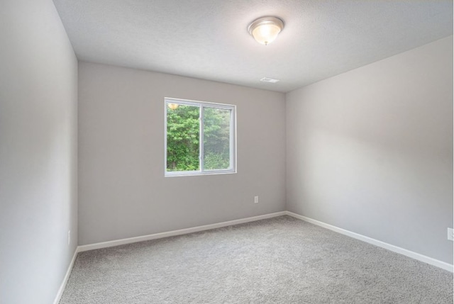 carpeted empty room featuring a textured ceiling