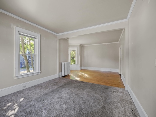 empty room featuring radiator, a wealth of natural light, ornamental molding, and hardwood / wood-style floors