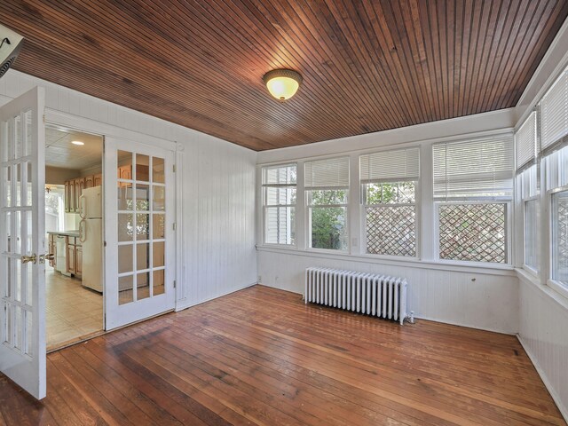 unfurnished sunroom featuring radiator heating unit, french doors, and wooden ceiling