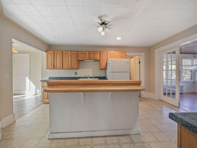 kitchen with radiator, sink, french doors, white refrigerator, and ornamental molding