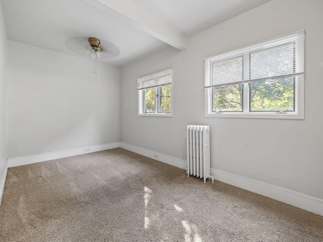 spare room with carpet, radiator heating unit, ceiling fan, and beam ceiling