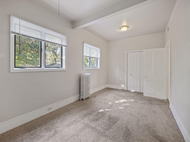 unfurnished room with beamed ceiling, radiator heating unit, carpet floors, and plenty of natural light