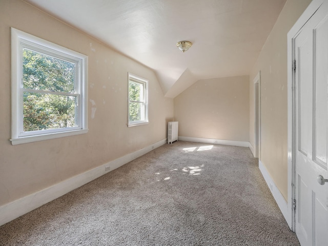 additional living space with carpet, radiator heating unit, and lofted ceiling