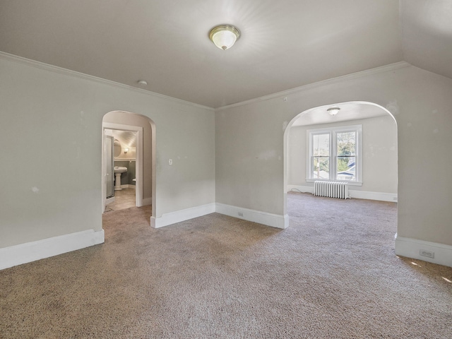 empty room with light colored carpet, crown molding, radiator, and vaulted ceiling