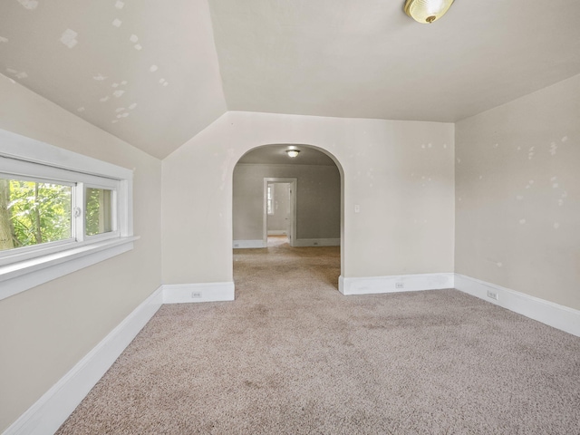 spare room with carpet flooring and lofted ceiling