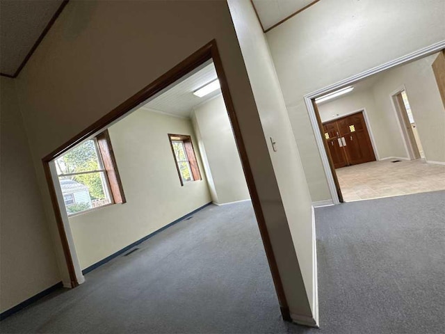 corridor featuring light colored carpet and crown molding